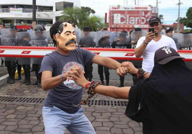 Un manifestante indossa una maschera che deride Daniel Ortega