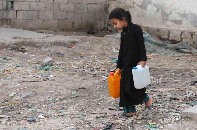 Una bambina trasporta taniche piene di acqua pulita da una pompa di beneficenza durante una continua crisi dell'acqua pulita nello Yemen