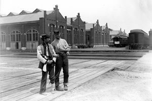 Due militari si trovano accanto al Pullman Building e addestrano vagoni con le braccia bloccate e una bottiglia di liquore durante lo sciopero del Pullman di Chicago del 1894