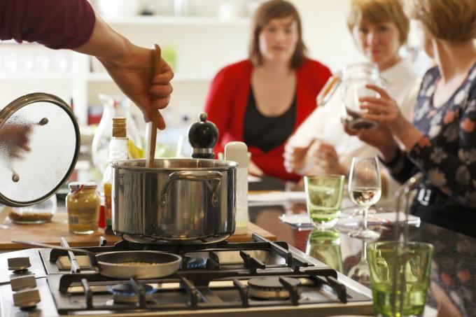 Mescolare una pentola su una stufa in un'isola cucina consente l'interazione con gli ospiti della cena.