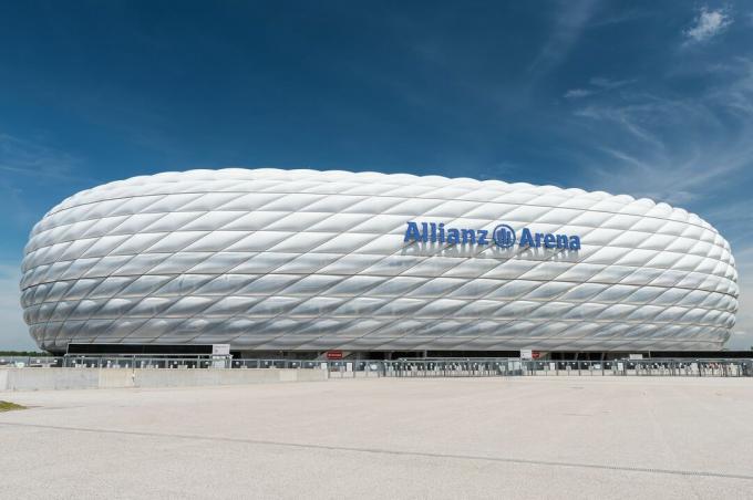 vista laterale dello stadio sportivo curvo, esterno scolpito di pannelli in plastica ETFE gonfiati, simile a una gomma calpestata bianca su un lato