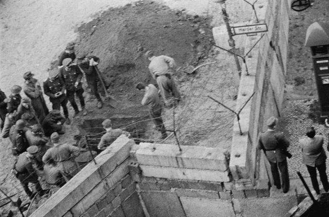 Un gruppo di soldati della Germania dell'Est indaga su un tunnel scavato sotto il muro di Berlino.