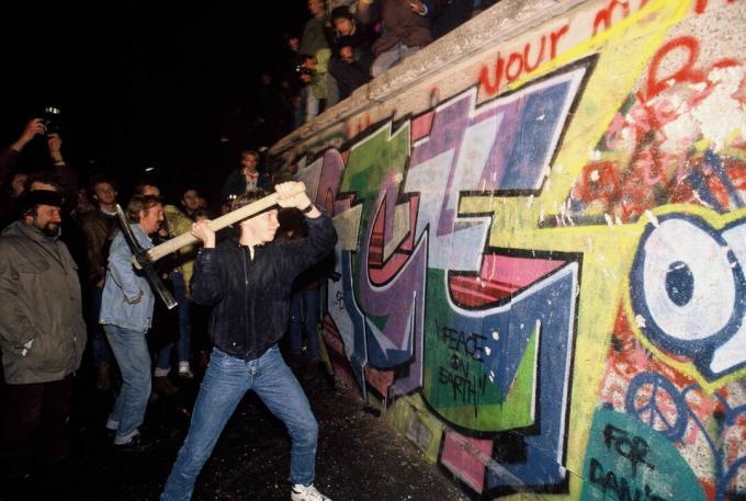 Un uomo attacca il muro di Berlino con un piccone nella notte del 9 novembre 1989