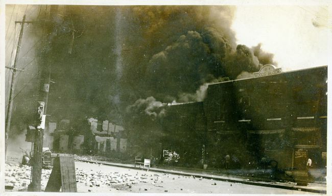 Proprietà danneggiate e fumo proveniente dagli edifici in seguito al massacro di Tulsa Race, Tulsa, Oklahoma, giugno 1921.