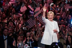 Hillary Clinton saluta la folla di persone che sventolano bandiere degli Stati Uniti