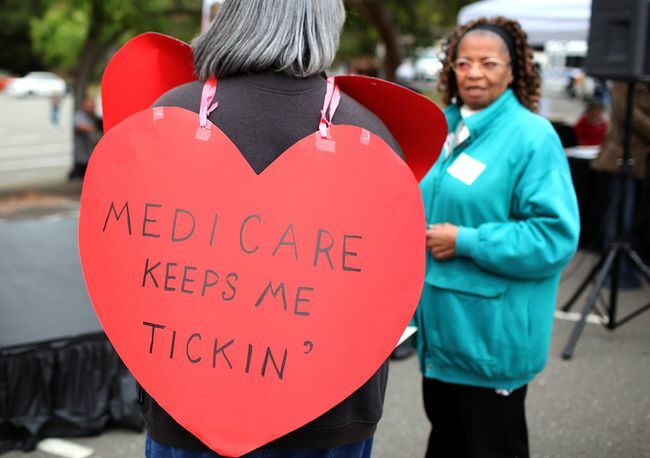 Donna che indossa un cartello a forma di cuore con la scritta " Medicare Keeps Me Ticking"