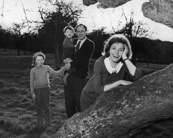 Foto in bianco e nero di Roald Dahl che tiene in braccio i suoi figli; sua moglie Patricia Neal si appoggia su un albero