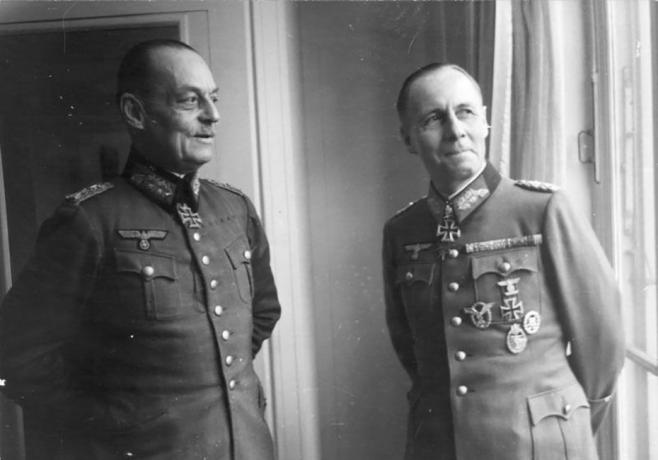 Gerd von Rundstedt ed Erwin Rommel in uniforme militare tedesca in piedi vicino a una finestra.