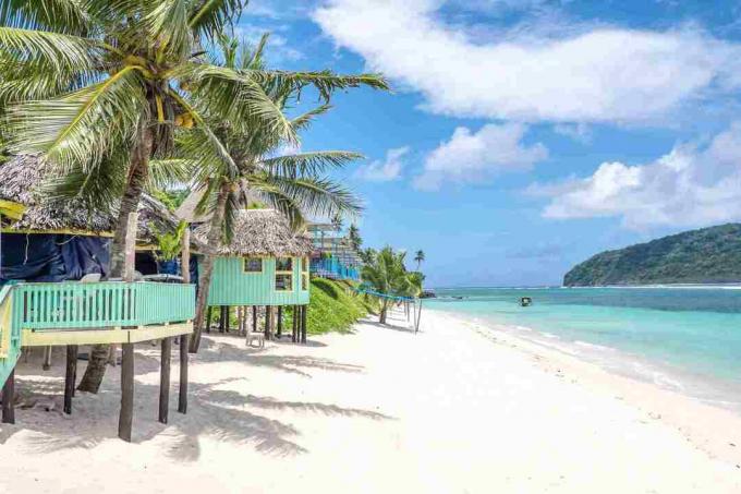 Vista lungo la spiaggia di Lalomanu, l'isola di Upolu, Samoa, delle colorate capanne di spiaggia samoana che sono un'alternativa alla sistemazione in hotel o resort