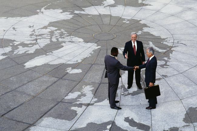  Regionalismo economico: uomini d'affari che si stringono la mano sulla mappa del globo.