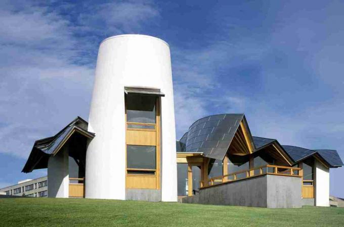 Edificio bianco simile a un cottage, tetto ondulato d'argento, Frank Gehry, torre bianca simile a un silo