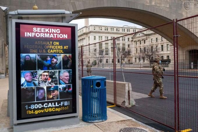 Un membro della guardia nazionale passa davanti a un poster in cerca di informazioni sull'attacco al Campidoglio degli Stati Uniti del 19 gennaio 2021.